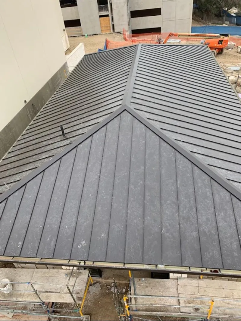 Commercial metal roof construction with crane equipment in Providence Village